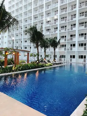 a swimming pool in front of a large building at Shore 1 Residences - ÜniQa Suite - MOA Area in Manila