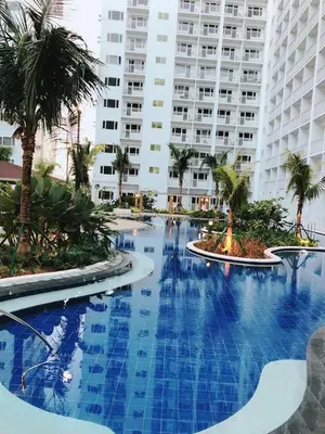 a large swimming pool with palm trees and a large building at Shore 1 Residences - ÜniQa Suite - MOA Area in Manila