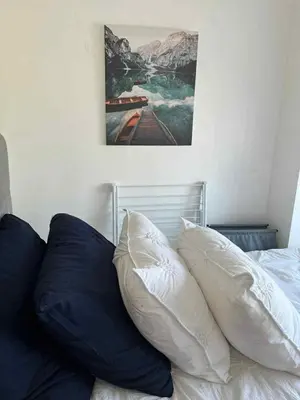 a bed with blue pillows and a picture on the wall at South Residences Tower 4, Las Pinas in Manila
