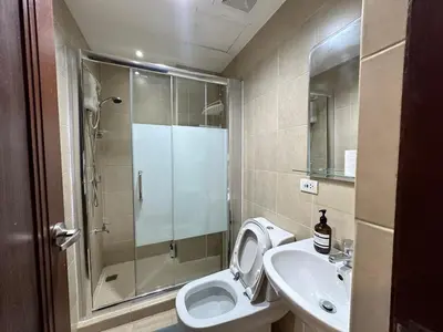 a bathroom with a shower and a toilet and a sink at Stylish 100 SQM 3BR Loft Near Greenbelt Makati in Manila