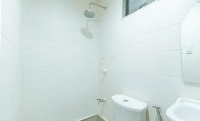 a white bathroom with a toilet and a sink at Maine Residences Leveriza by RedDoorz in Manila
