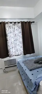 a bedroom with a bed and a window with a curtain at Graxia staycation in Manila