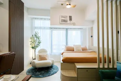 a bedroom with a bed and a chair and a window at Breathtaking Eastwood City View, 3min walk to Malls, with Washer in Manila