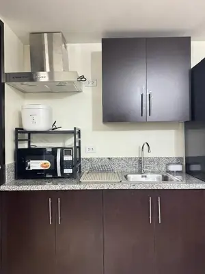 a kitchen with dark brown cabinets and a sink at City Lights and Cozy nights in Manila