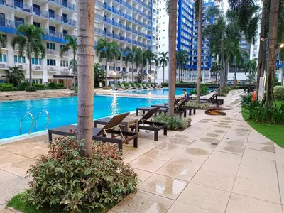 a swimming pool with tables and benches next to a building at SEA RESIDENCES Golden in Manila