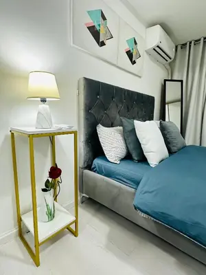 a bedroom with a blue bed and a table with a lamp at Affordable Boracay-like Staycation in Azure South in Manila