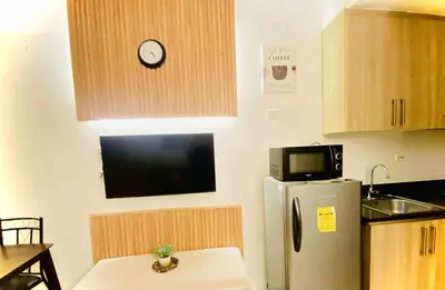 a kitchen with a refrigerator and a clock on the wall at Shore Residences in Manila