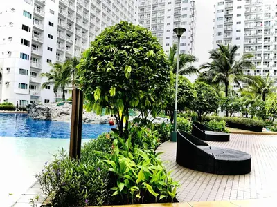 a pool with benches and a tree and buildings at Shore Residences in Manila