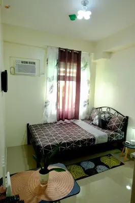 a small bedroom with a bed with a window at Cecils Cubao Cozy Escape in Manila