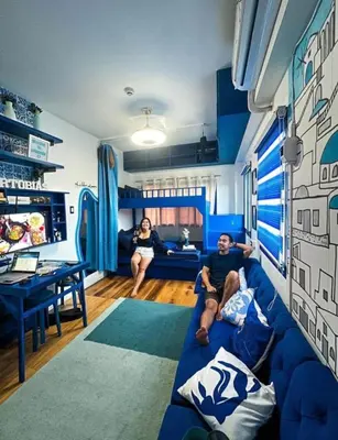 a man and woman sitting on a blue couch in a living room at Valley Mansions Staycation near Taytay in Cainta