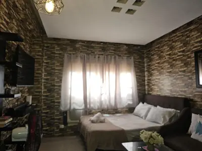 a bedroom with a bed and a couch and a window at Staycation in Valley Mansions near Taytay in Cainta
