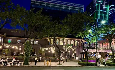 a building with people sitting outside at night at Cozy place in Uptown BGC near Malls and clubs in Manila