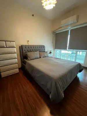 a bedroom with a large bed and a window at Amorsolo Tower Makati in Manila