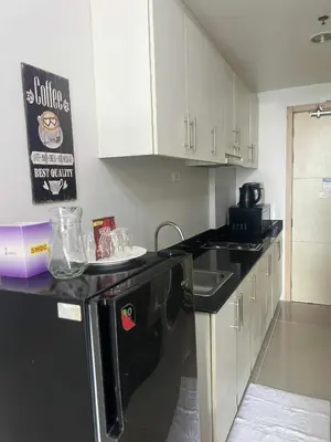a kitchen with white cabinets and a black dishwasher at V&G Staycation in Manila