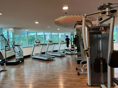 a gym with a row of treadmills and a man in the background at 55-SQM 1-BR golf club view condo in Central BGC in Manila