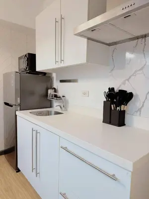 a white kitchen with a sink and a refrigerator at Stunning 42nd Floor Apt with Netflix in Manila