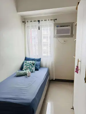 a bedroom with a blue bed with a window at Bloom Residence by SMDC in Manila