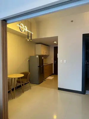 a kitchen and dining room with a table and a refrigerator at Cozy 1-Bedroom in Uptown Parksuites BGC in Manila