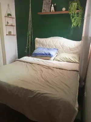 a bed in a bedroom with a green wall at Vacation Home by Rowena Sacarez in Trece Martires