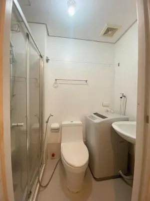 a bathroom with a toilet and a shower and a sink at Light Residence Condo with Balcony and Pool View in Manila