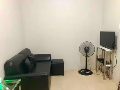 a living room with a black leather couch and a fan at 1 BR Taytay HIVE Condo WIFI Netflix Pool Patio in Taytay