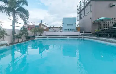 a large blue swimming pool next to a building at Urban Travellers Hotel by RedDoorz in Manila