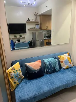 a blue couch with pillows in a living room at MOA Staycation Condotel PASAY in Manila