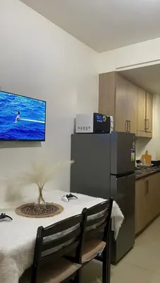a kitchen with a table and a tv on the wall at HJ Haven in Manila
