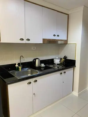 a kitchen with white cabinets and a sink at Chateau Lumiere Staycation at MOA in Manila