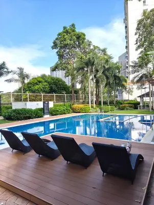 a swimming pool with chairs on a wooden deck at Studio City Staycation in Alabang in Manila