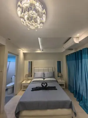 a bedroom with a bed with a pair of scissors on it at 2 BEDROOM SHELL RESIDENCES MOA view in Manila