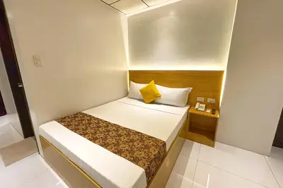 a small bedroom with a bed with a yellow pillow at LuxeLite Suites Pasay in Pasay