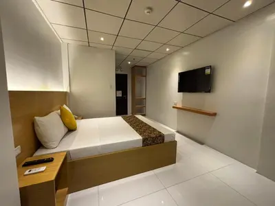 a bedroom with a bed and a tv on the wall at LuxeLite Suites Pasay in Pasay