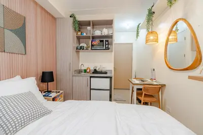a bedroom with a bed and a small kitchen at SSM Staycation in Manila