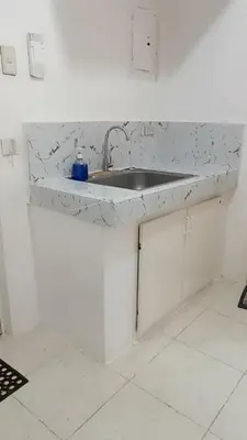 a white kitchen with a sink and a counter at Capsule88 Hotel in Manila
