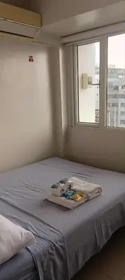 a bed with a towel on it in a room with a window at Solemare Parksuites - no balcony in Manila