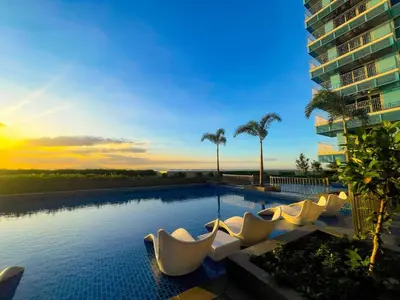 a swimming pool with white chairs and a building at Luxury 1-Bedroom Apartment Across Okada Manila in Manila