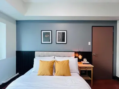 a bedroom with a blue wall with a bed and a desk at Spacious 1BR with 300MBPS Internet near High Street BGC in Manila