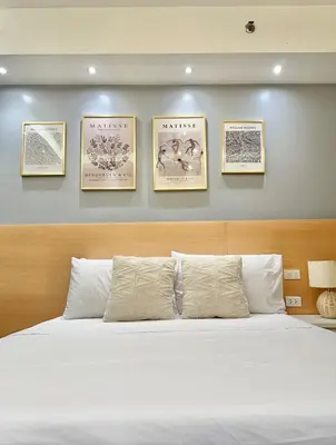 a bedroom with a bed with four pictures on the wall at Stylish Studio Unit with Balcony in Grace Residences in Manila