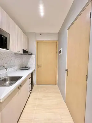 a kitchen with a wooden door and a sink at Stylish Studio Unit with Balcony in Grace Residences in Manila