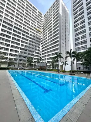 a large blue swimming pool in front of tall buildings at Stylish Studio Unit with Balcony in Grace Residences in Manila