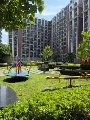 a park with a playground in front of a large building at Condo Monarch Parksuites in Sampong