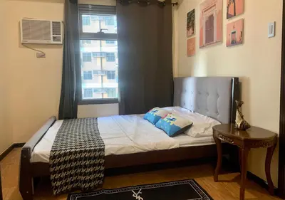 a small bedroom with a bed with a window at Manila Bay Condo in Manila
