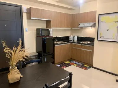 a small kitchen with a table and a black refrigerator at Manila Bay Condo in Manila