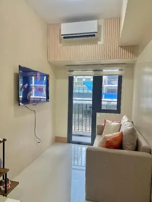 a living room with a couch and a flat screen tv at Soléa Suites in Manila