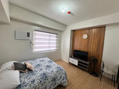 a bedroom with a bed and a flat screen tv at Mels Place at Tulip Garden Condominium Southwoods in Biñan