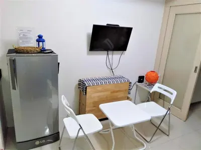 a kitchen with two white chairs and a television at My Cozy Little Crib - Sea Residence - Tower C in Manila