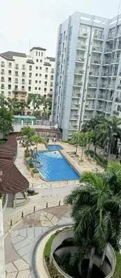 a view of a pool in a park with tall buildings at Kmad's Condotel in Manila