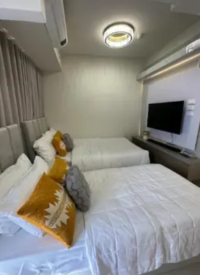 a bedroom with two beds and a flat screen tv at Sweet Escape at S Residences in Manila