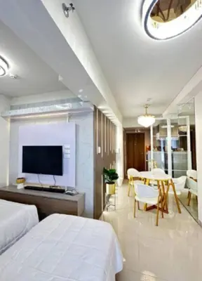 a bedroom with two beds and a table and a tv at Sweet Escape at S Residences in Manila
